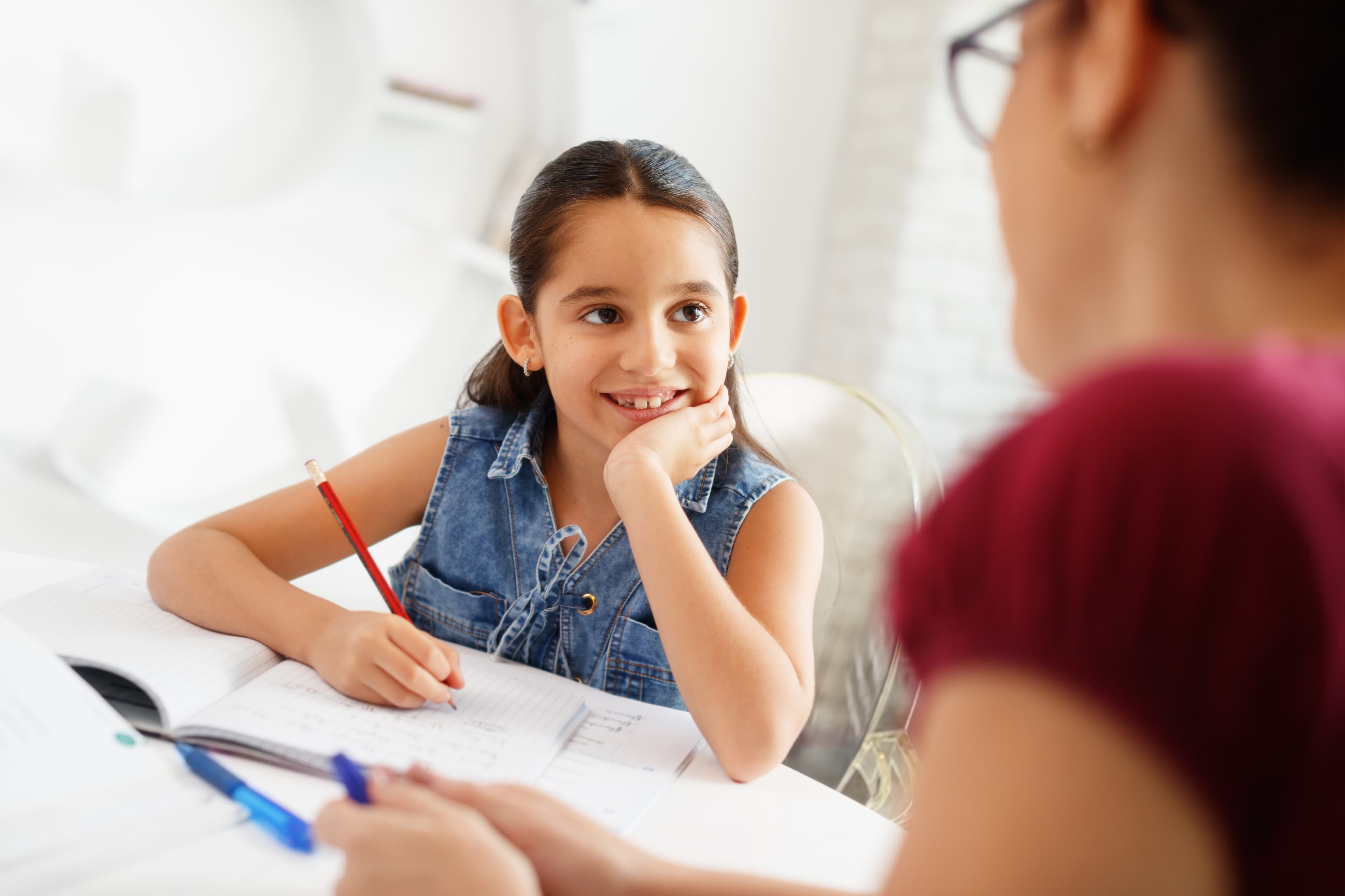 A student smiling at her tutor across the table during a lesson